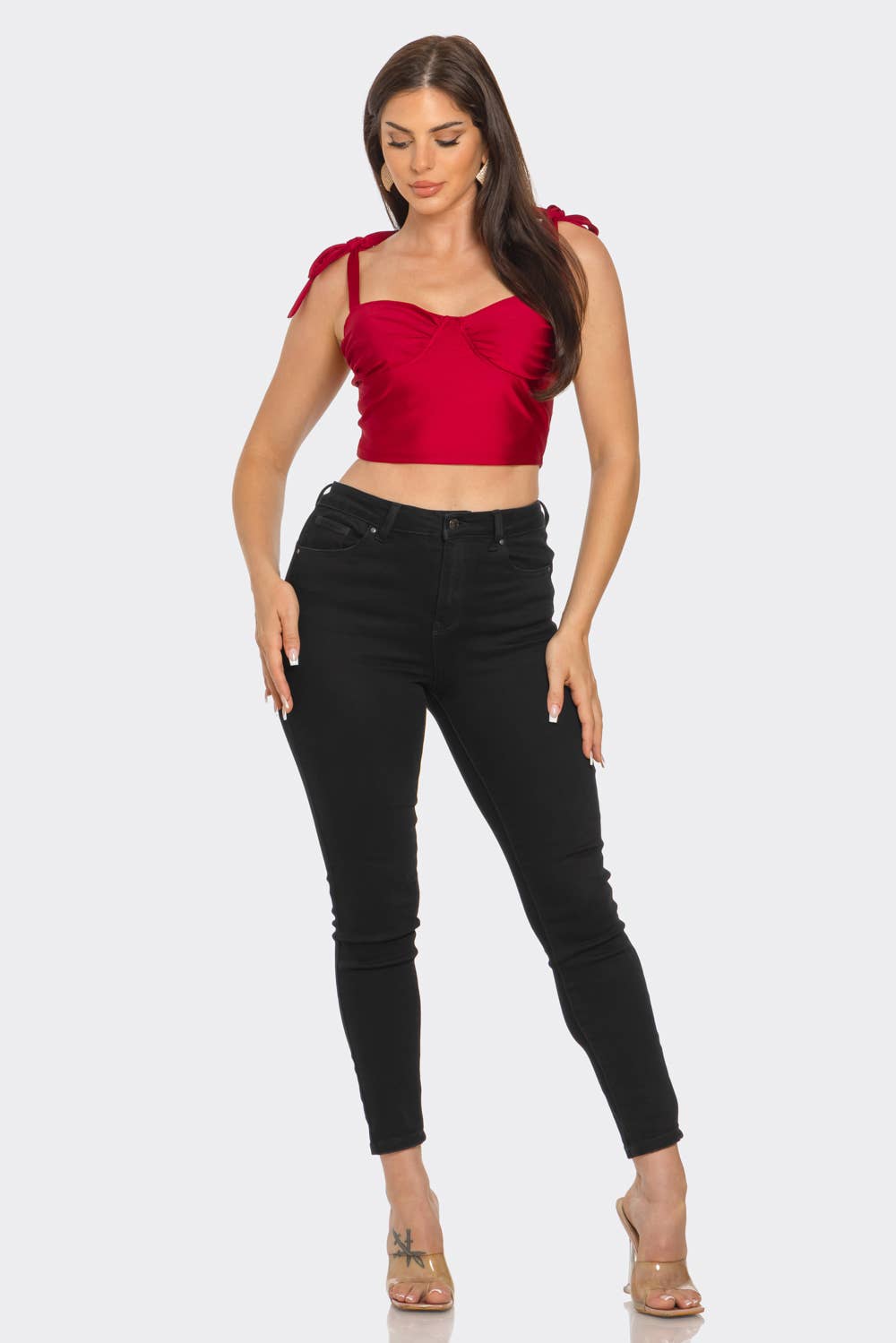 Woman wearing a red top and black jeans on a white background